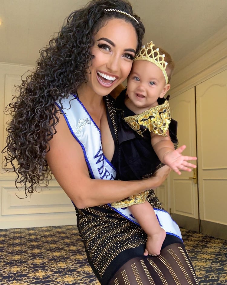 Coach with her baby daugher are dressup and little girl having a gold crown on her head.